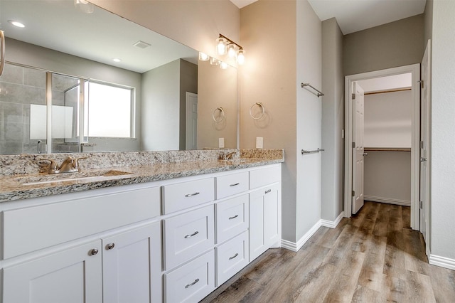 430 Mitchell Blvd, Weatherford, TX 76087 - bathroom with double vanity, wood finished floors, baseboards, a walk in closet, and tiled shower