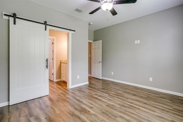 430 Mitchell Blvd, Weatherford, TX 76087 - unfurnished bedroom featuring a barn door, wood finished floors, baseboards, and a ceiling fan