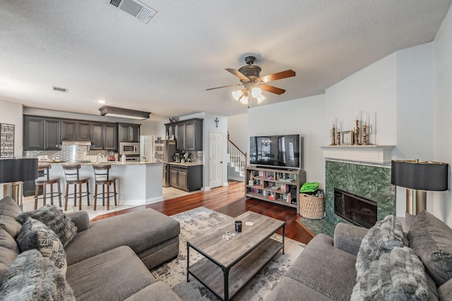 2508 Springhill Dr, Grapevine, TX 76051 - living room featuring a ceiling fan, light wood finished floors, a high end fireplace, a textured ceiling, and stairs