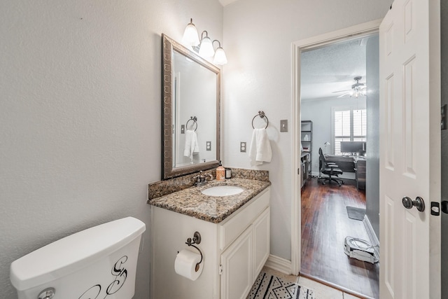 2508 Springhill Dr, Grapevine, TX 76051 - half bathroom with vanity, toilet, wood finished floors, and a ceiling fan