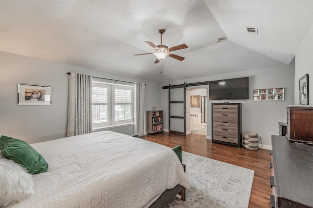 2508 Springhill Dr, Grapevine, TX 76051 - bedroom featuring a barn door, wood finished floors, a textured ceiling, baseboards, and a ceiling fan