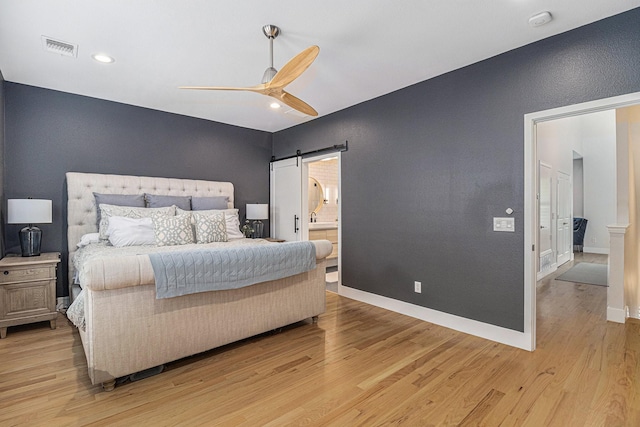 724 E Bluff St, Fort Worth, TX 76102 - bedroom with a barn door, light wood-style floors, baseboards, ceiling fan, and ensuite bathroom