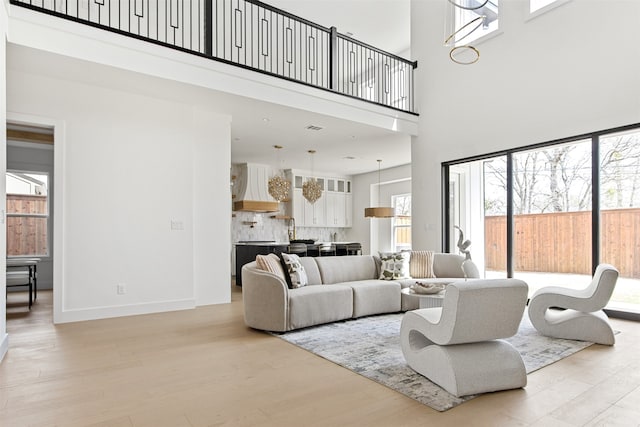 9974 Witham St, Dallas, TX 75220 - living area featuring a towering ceiling, light wood finished floors, and baseboards