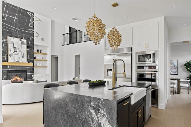 9974 Witham St, Dallas, TX 75220 - kitchen with built in appliances, a sink, an island with sink, light wood-style flooring, and dark cabinets