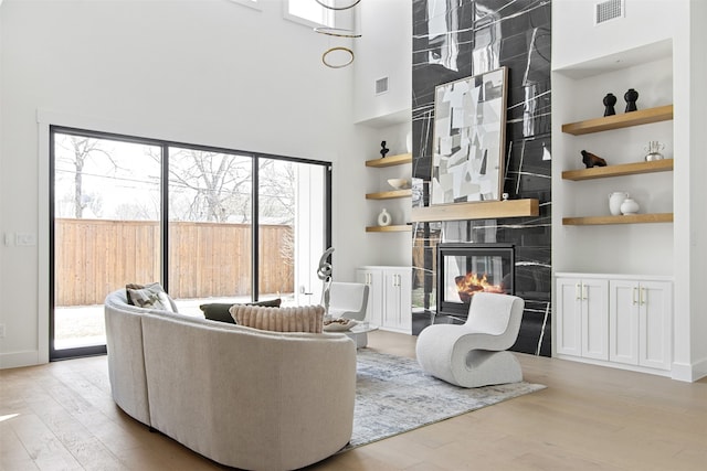 9974 Witham St, Dallas, TX 75220 - living room with wood finished floors, a high ceiling, built in shelves, and a tile fireplace