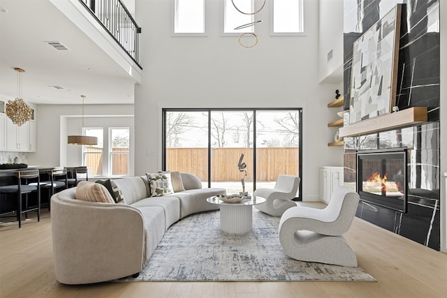 9974 Witham St, Dallas, TX 75220 - living area featuring a towering ceiling, wood finished floors, a glass covered fireplace, and plenty of natural light