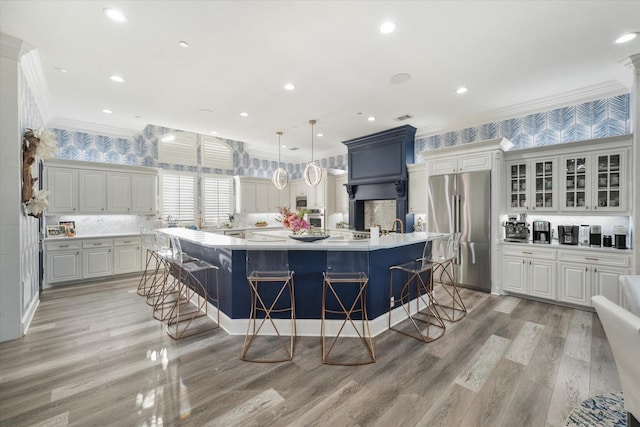 1705 Bison Meadow Ln, Heath, TX 75032 - kitchen with stainless steel appliances, crown molding, a kitchen bar, light countertops, and a large island with sink