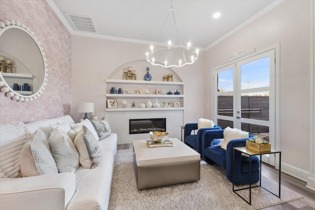 1705 Bison Meadow Ln, Heath, TX 75032 - living area with wood finished floors, a chandelier, a glass covered fireplace, ornamental molding, and built in shelves