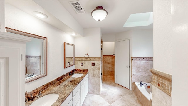 2212 Creekwood Ct, Flower Mound, TX 75028 - bathroom with tile walls, a bath, double vanity, tile patterned floors, and wainscoting