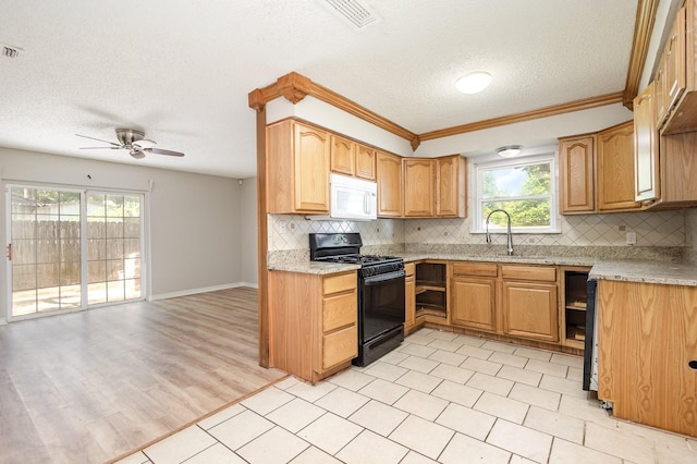 2200 Clover Park Dr, Arlington, TX 76013 - kitchen with black gas stove, white microwave, a textured ceiling, decorative backsplash, and a ceiling fan