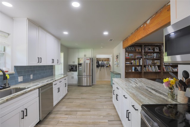 7251 Valley Dale Ct, Benbrook, TX 76116 - kitchen with appliances with stainless steel finishes, a sink, light wood-style flooring, light stone counters, and white cabinetry