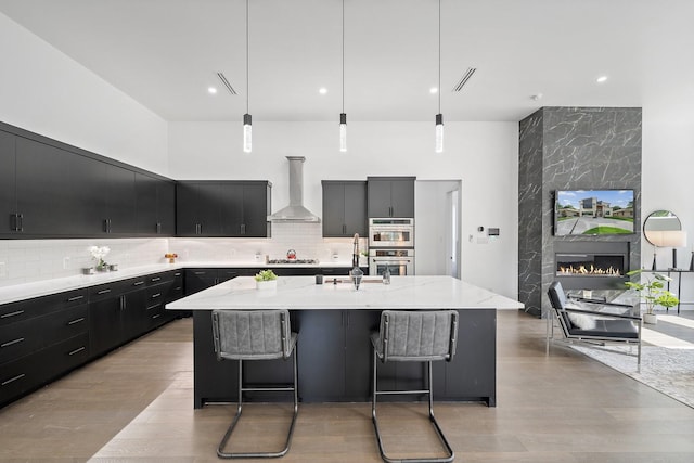 4233 Skillman St, Dallas, TX 75206 - kitchen featuring wall chimney exhaust hood, dark cabinets, a sink, stainless steel appliances, and backsplash