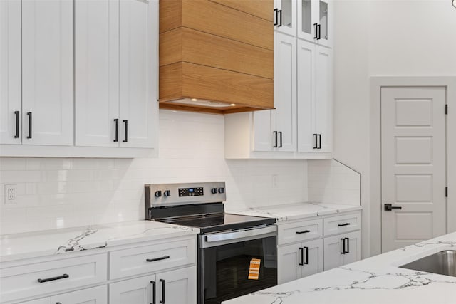 5845 Black Pine Cir, Granbury, TX 76048 - kitchen with stainless steel range with electric stovetop, white cabinets, custom range hood, light stone countertops, and decorative backsplash