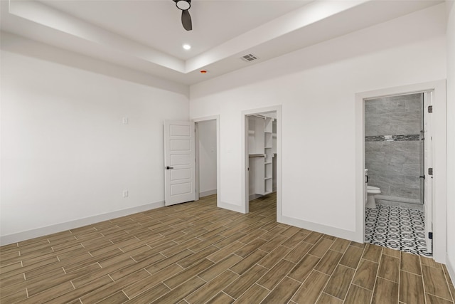 5845 Black Pine Cir, Granbury, TX 76048 - unfurnished bedroom featuring wood finished floors, baseboards, a raised ceiling, a walk in closet, and recessed lighting