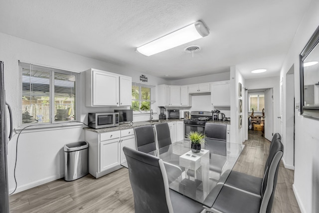 2605 Himes St, Irving, TX 75060 - dining area with light wood-style floors, baseboards, and a textured ceiling