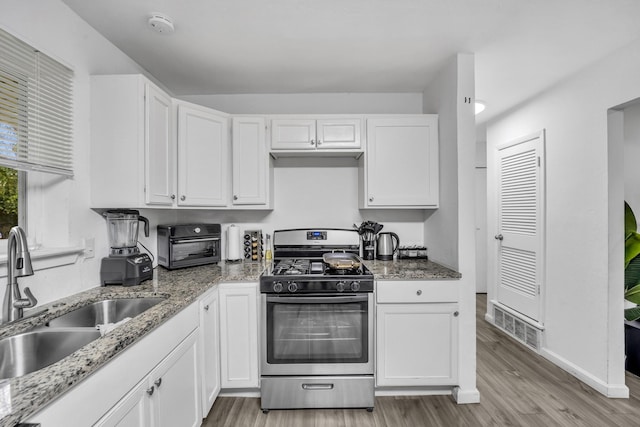 2605 Himes St, Irving, TX 75060 - kitchen featuring stainless steel range with gas stovetop, a sink, light wood-type flooring, white cabinets, and light stone counters