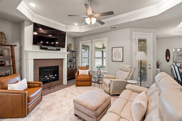 7700 Cerrito Trl, Fort Worth, TX 76123 - living room featuring a raised ceiling, a ceiling fan, wood finished floors, a brick fireplace, and crown molding