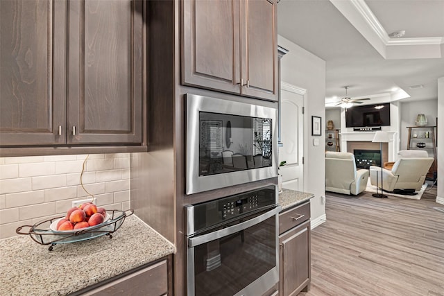 7700 Cerrito Trl, Fort Worth, TX 76123 - kitchen with built in microwave, stainless steel oven, tasteful backsplash, light stone counters, and a glass covered fireplace