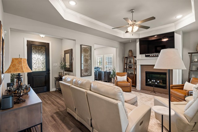 7700 Cerrito Trl, Fort Worth, TX 76123 - living area with a tray ceiling, a ceiling fan, dark wood-type flooring, a tile fireplace, and ornamental molding