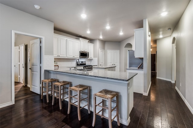 2637 Hillrich Dr, Anna, TX 75409 - kitchen with arched walkways, appliances with stainless steel finishes, dark wood-type flooring, white cabinets, and a peninsula