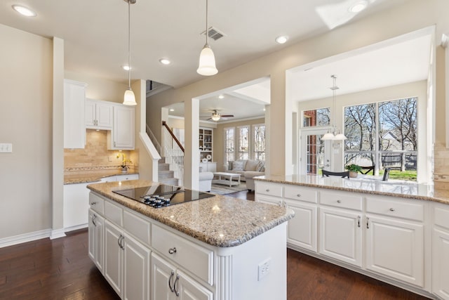 1415 Cambridge Xing, Southlake, TX 76092 - kitchen with black electric stovetop, backsplash, ceiling fan, a kitchen island, and dark wood-style flooring