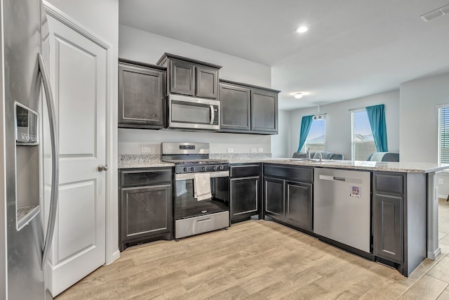 9752 New Bern Dr, Fort Worth, TX 76108 - kitchen with appliances with stainless steel finishes, a peninsula, light wood finished floors, light stone countertops, and recessed lighting