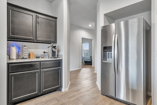 9752 New Bern Dr, Fort Worth, TX 76108 - kitchen featuring stainless steel fridge, light wood-style flooring, baseboards, light stone counters, and dark brown cabinets
