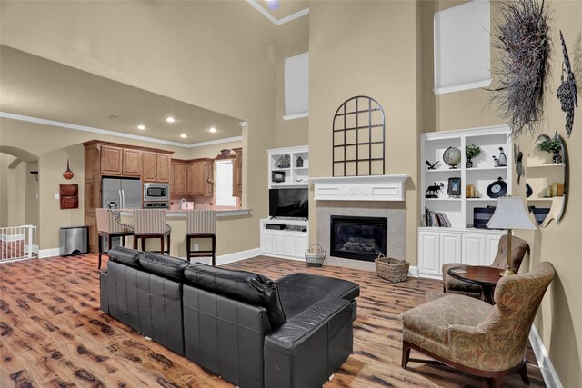 7904 Chickasaw Trl, Mckinney, TX 75070 - living room with ornamental molding, arched walkways, baseboards, light wood-style flooring, and a high ceiling