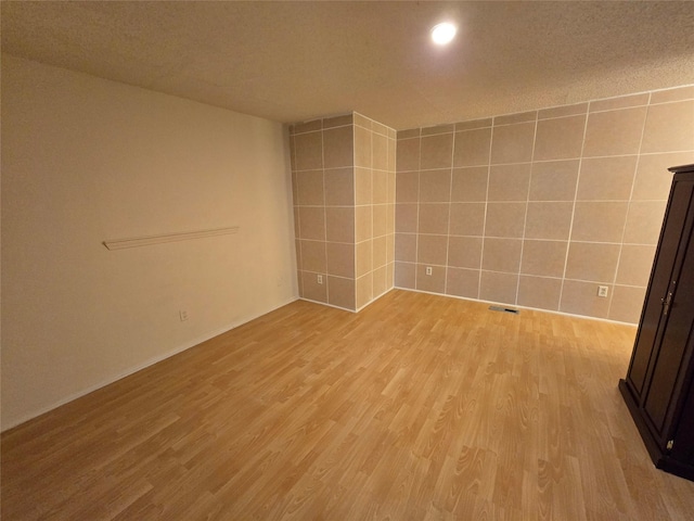9835 Walnut St Unit 203, Dallas, TX 75243 - spare room with light wood finished floors, a textured ceiling, and tile walls
