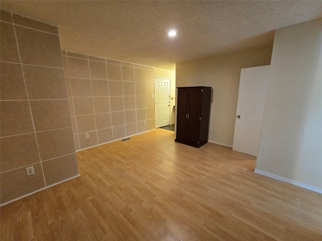 9835 Walnut St Unit 203, Dallas, TX 75243 - spare room featuring tile walls, light wood-type flooring, a textured ceiling, recessed lighting, and baseboards