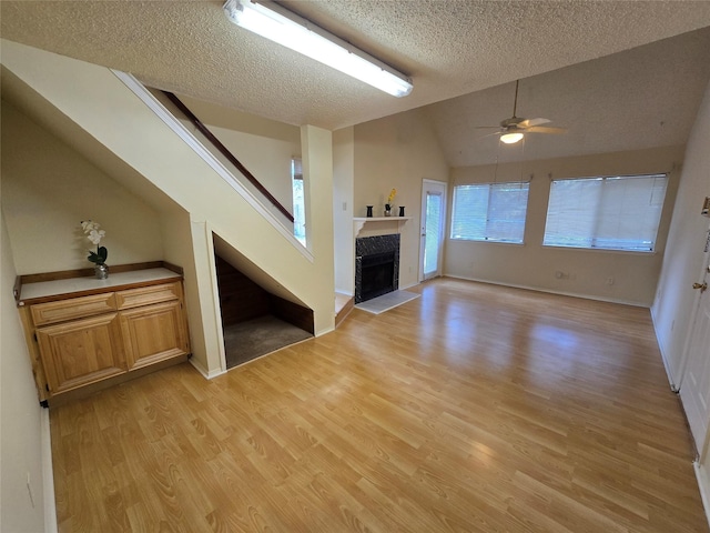 9835 Walnut St Unit 203, Dallas, TX 75243 - unfurnished living room featuring a textured ceiling, vaulted ceiling, light wood-type flooring, ceiling fan, and stairway