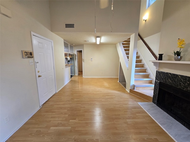 9835 Walnut St Unit 203, Dallas, TX 75243 - living area with light wood finished floors, a high ceiling, baseboards, stairway, and a high end fireplace