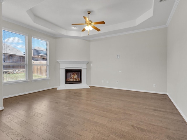 125 Gill Point Ln, Aledo, TX 76008 - unfurnished living room with a raised ceiling, wood finished floors, ceiling fan, a glass covered fireplace, and ornamental molding