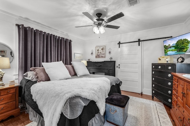 6440 Harmonson Rd, North Richland Hills, TX 76180 - bedroom with a barn door, wood finished floors, and a ceiling fan