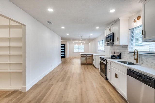 611 Cannon Dr, Euless, TX 76040 - kitchen with appliances with stainless steel finishes, a sink, light wood-style floors, a peninsula, and recessed lighting