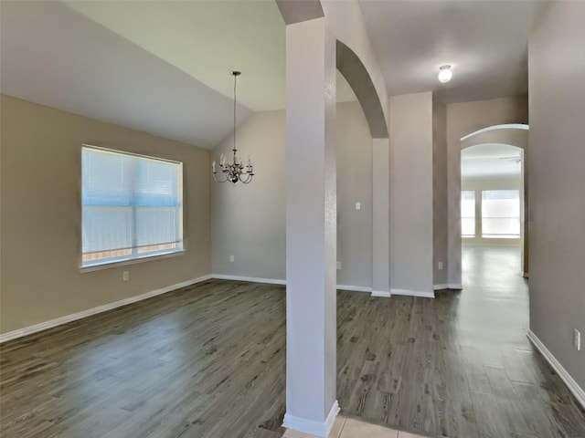 529 Covey Trl, Rockwall, TX 75087 - unfurnished dining area with arched walkways, wood finished floors, a chandelier, baseboards, and vaulted ceiling