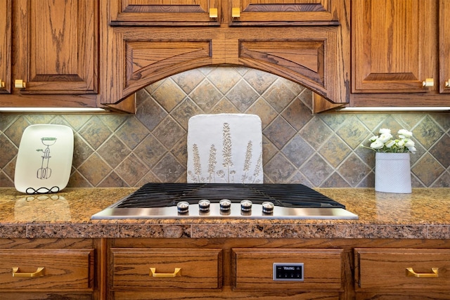 1632 Coyote Rdg, Carrollton, TX 75010 - kitchen featuring stainless steel gas stovetop, brown cabinetry, and backsplash