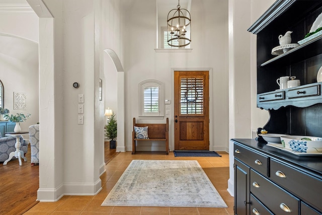 1632 Coyote Rdg, Carrollton, TX 75010 - foyer with arched walkways, a chandelier, light tile patterned floors, a high ceiling, and baseboards