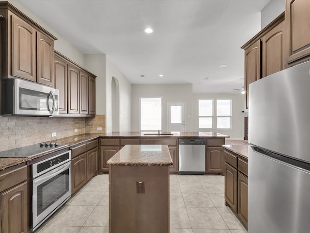 14824 Angel Trace Dr, Aledo, TX 76008 - kitchen with stainless steel appliances, a peninsula, tasteful backsplash, a center island, and dark stone counters