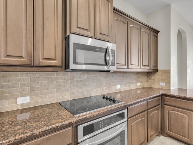 14824 Angel Trace Dr, Aledo, TX 76008 - kitchen featuring appliances with stainless steel finishes, dark stone countertops, decorative backsplash, and arched walkways