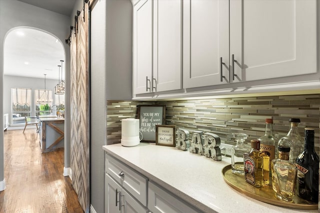1741 Mountain Creek Ln, Prosper, TX 75078 - bar with backsplash, wood finished floors, and arched walkways