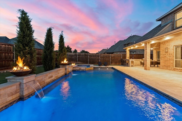 1741 Mountain Creek Ln, Prosper, TX 75078 - pool at dusk with a fire pit, a patio, a fenced backyard, and a pool with connected hot tub