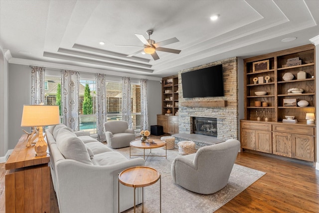 1741 Mountain Creek Ln, Prosper, TX 75078 - living room featuring a raised ceiling, a ceiling fan, wood finished floors, a stone fireplace, and built in shelves