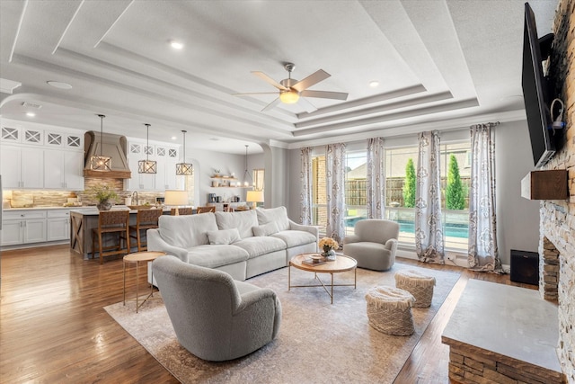 1741 Mountain Creek Ln, Prosper, TX 75078 - living area with a tray ceiling, a ceiling fan, a fireplace, and light wood-style flooring