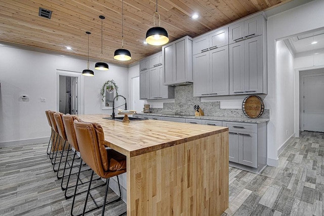 7336 Saint Augustine Dr, Cleburne, TX 76033 - kitchen featuring a sink, wood ceiling, decorative backsplash, baseboards, and a breakfast bar