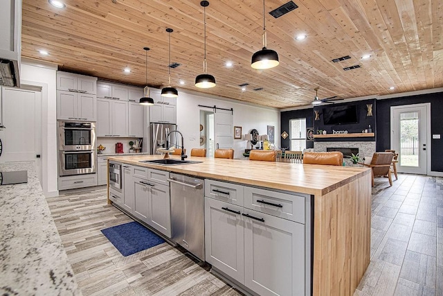 7336 Saint Augustine Dr, Cleburne, TX 76033 - kitchen with butcher block countertops, a sink, appliances with stainless steel finishes, open floor plan, and a barn door