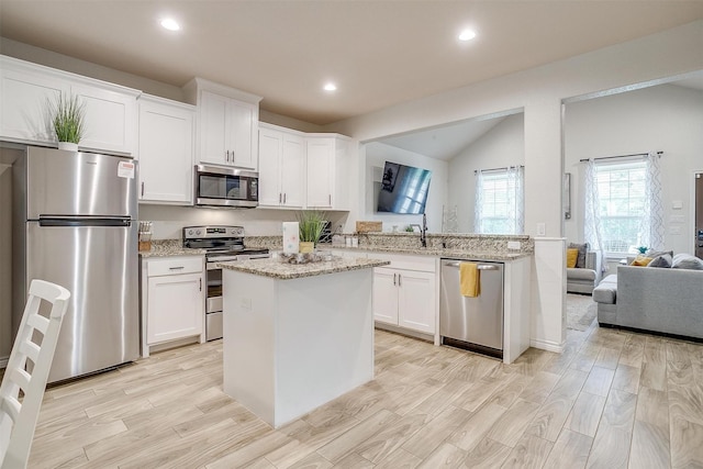 3108 Ridgecrest Dr, Granbury, TX 76048 - kitchen with appliances with stainless steel finishes, vaulted ceiling, white cabinetry, light wood finished floors, and recessed lighting