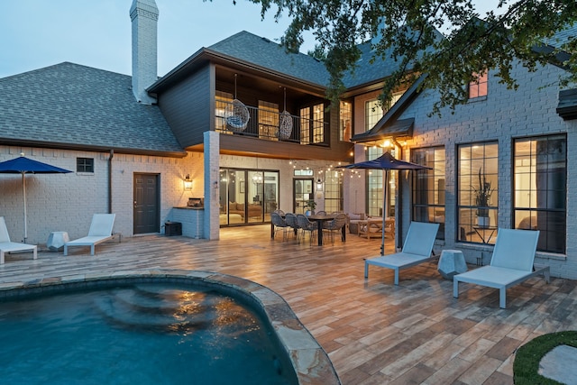 5934 Shy Dr, Frisco, TX 75034 - rear view of house featuring a balcony, roof with shingles, a chimney, an outdoor pool, and a patio