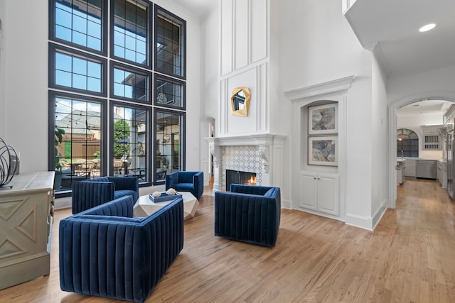 5934 Shy Dr, Frisco, TX 75034 - living area with arched walkways, light wood-style floors, ornamental molding, a tile fireplace, and a high ceiling