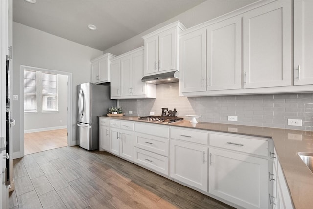 3604 Hidden Hollow Dr, Grand Prairie, TX 76065 - kitchen featuring stainless steel appliances, white cabinetry, under cabinet range hood, and tasteful backsplash